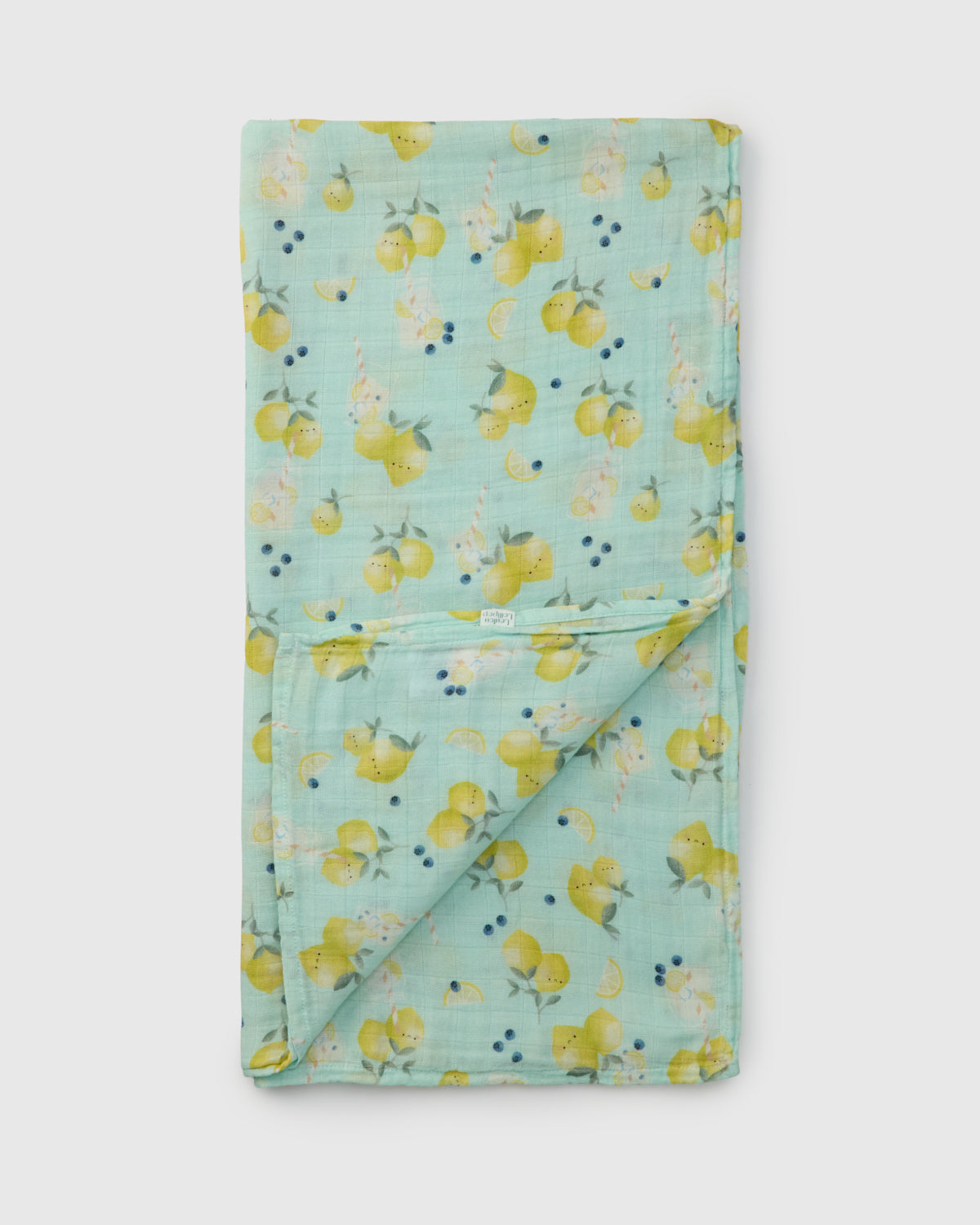 Folded fabric muslin swaddle with lemon pattern on a light blue background