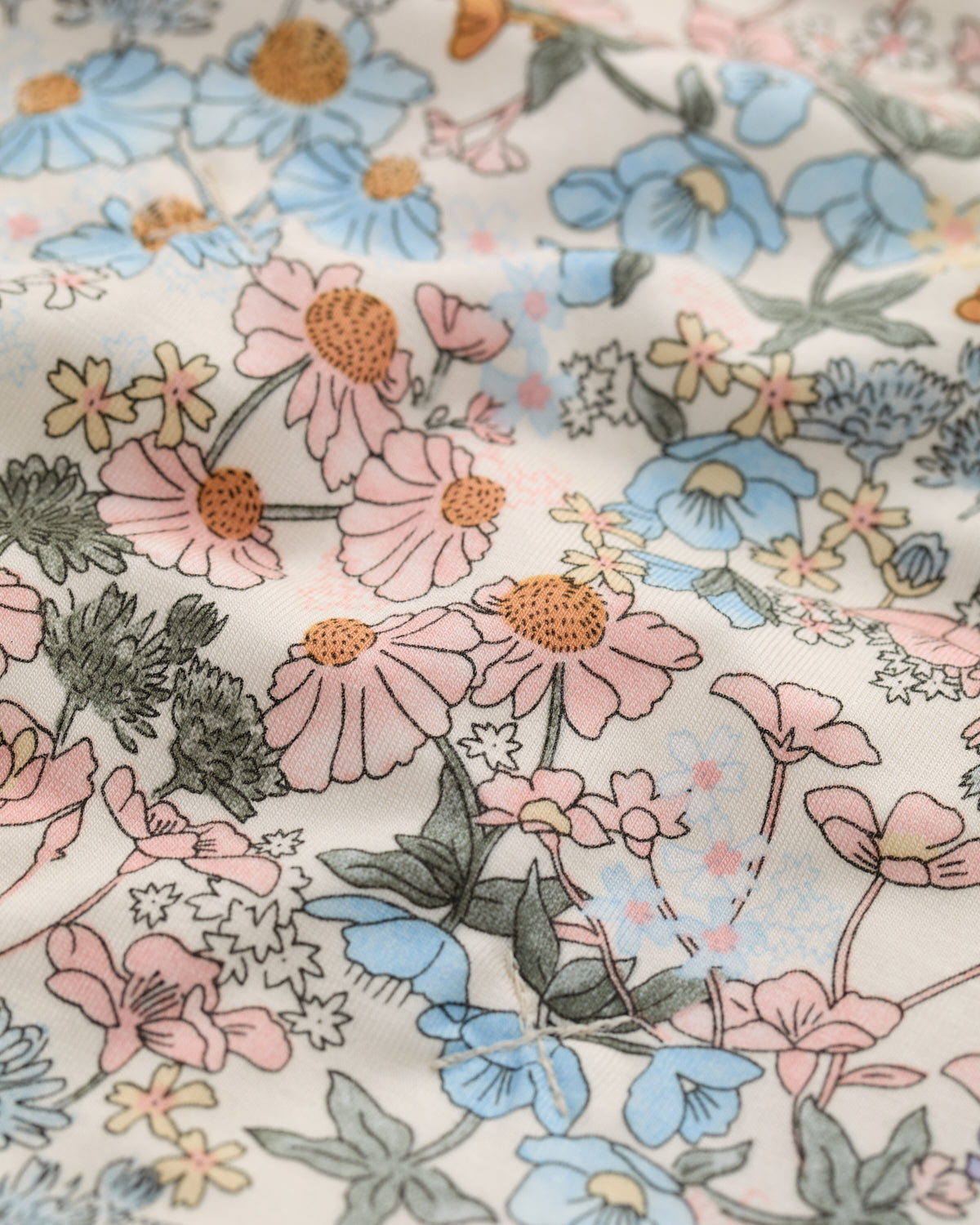 Close-up of floral fabric with pink, blue, and green flowers.