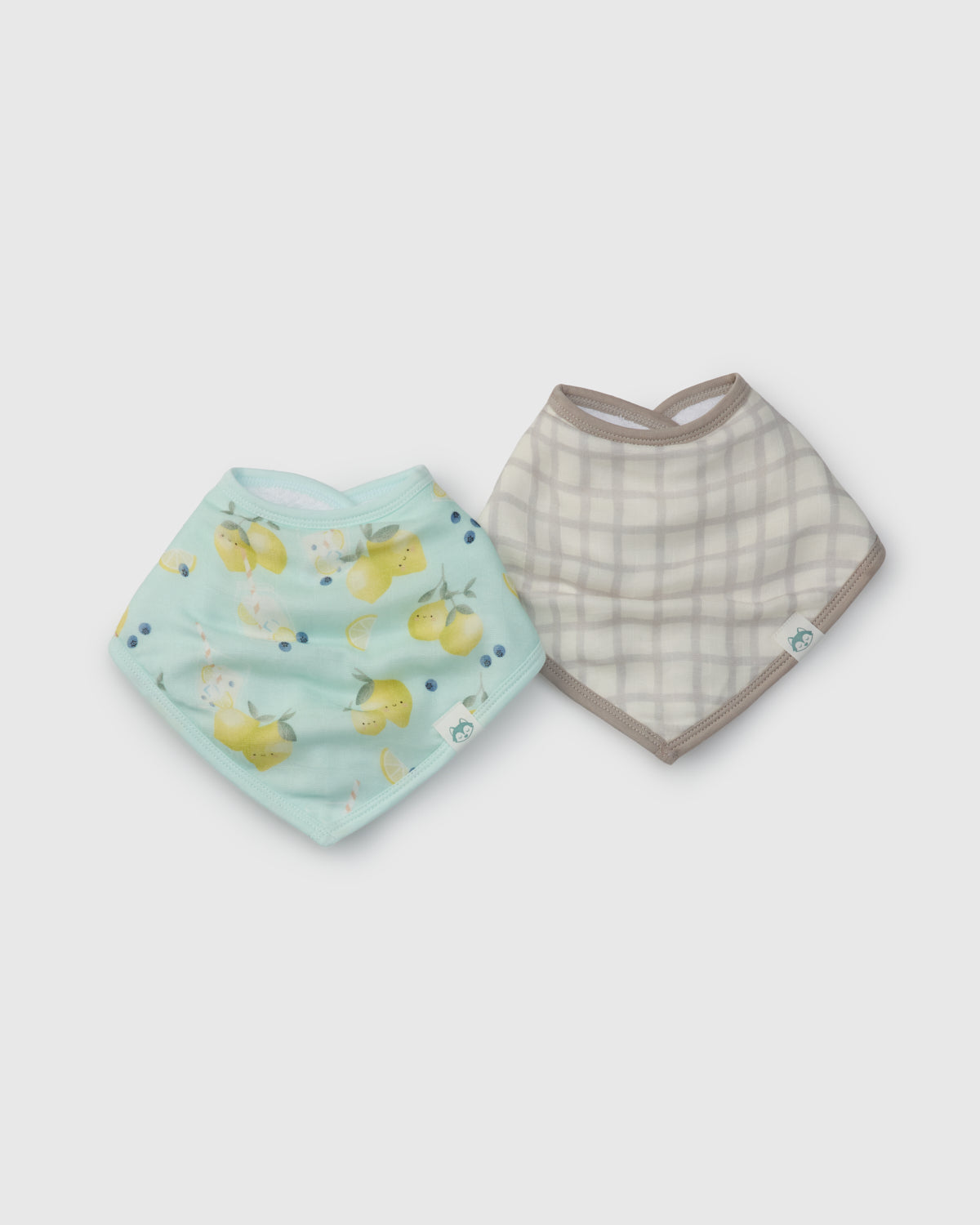 Two baby bibs, one with lemon pattern and one with checkered pattern, on a light gray background.