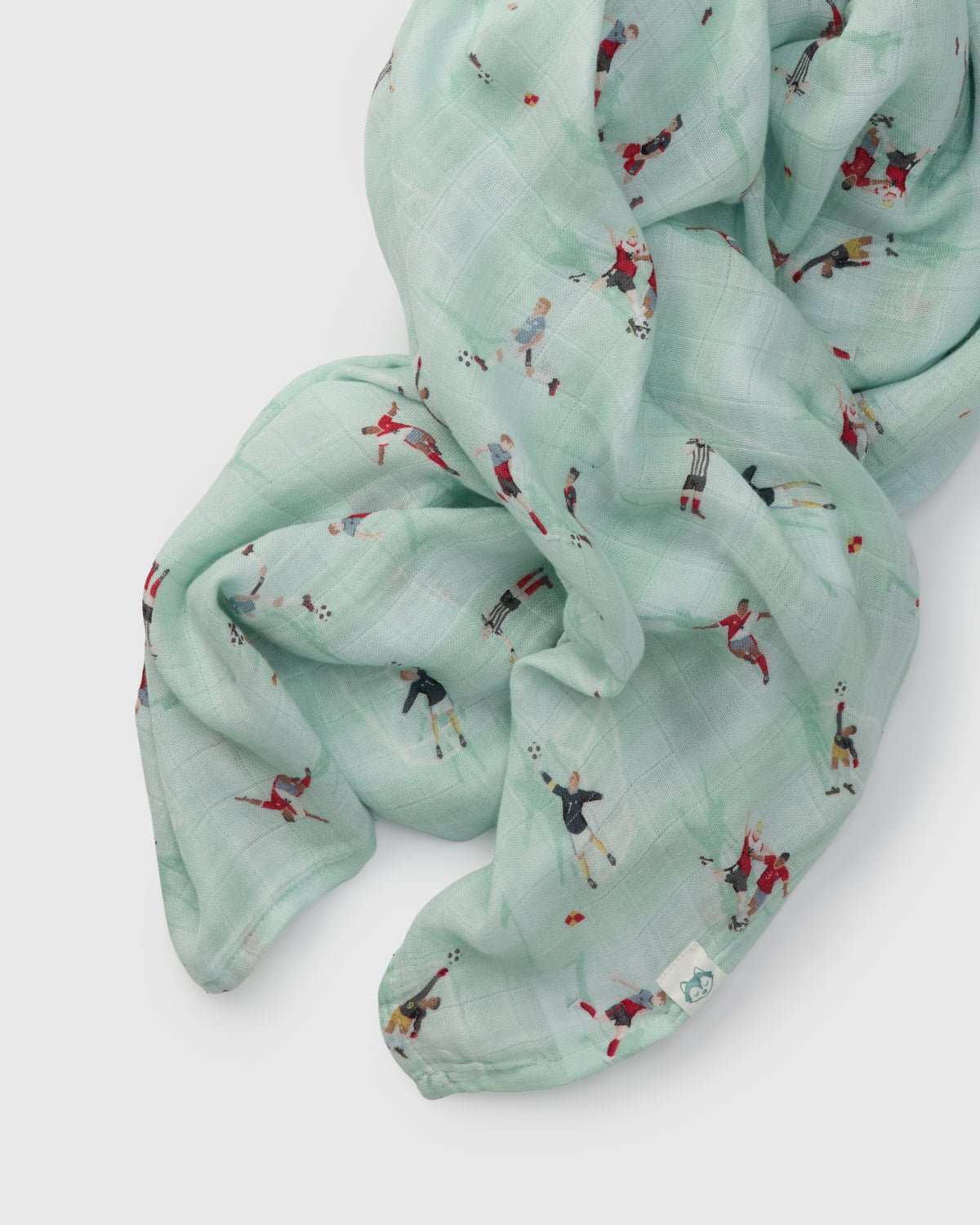 Light blue muslin swaddle  with small soccer printed designs on a white background