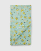 Folded fabric muslin swaddle with lemon pattern on a light blue background